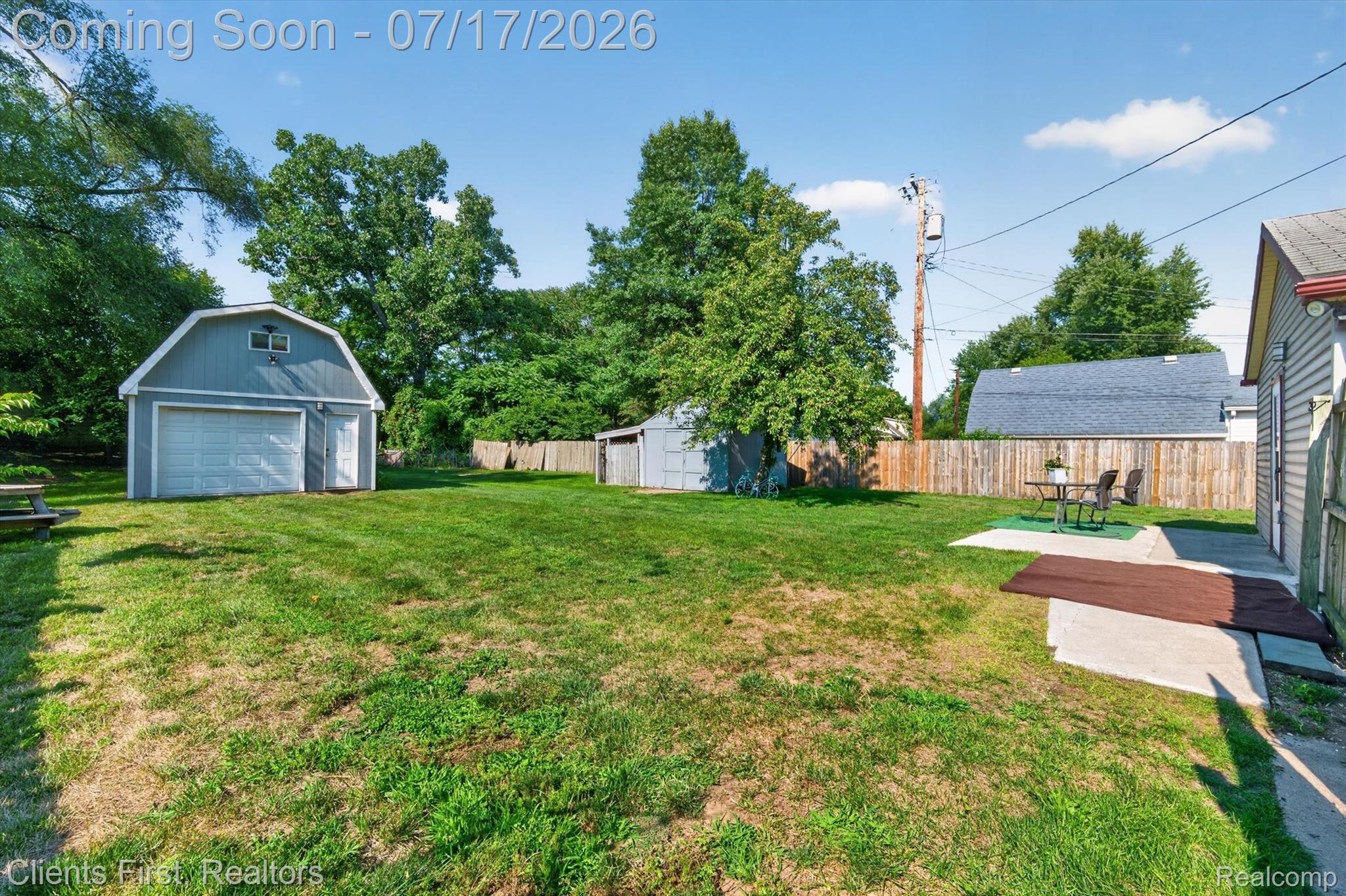 36852 Chase Street Romulus, MI 48174 - Photo 35 of 40 Spacious backyard featuring a detached garage with an overhead door, a privacy fence, a concrete patio, and mature trees