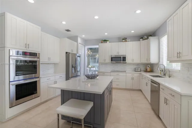 a large kitchen with cabinets stainless steel appliances a sink and a counter top space