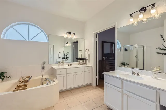 a bathroom with a double vanity sink mirror and bathtub