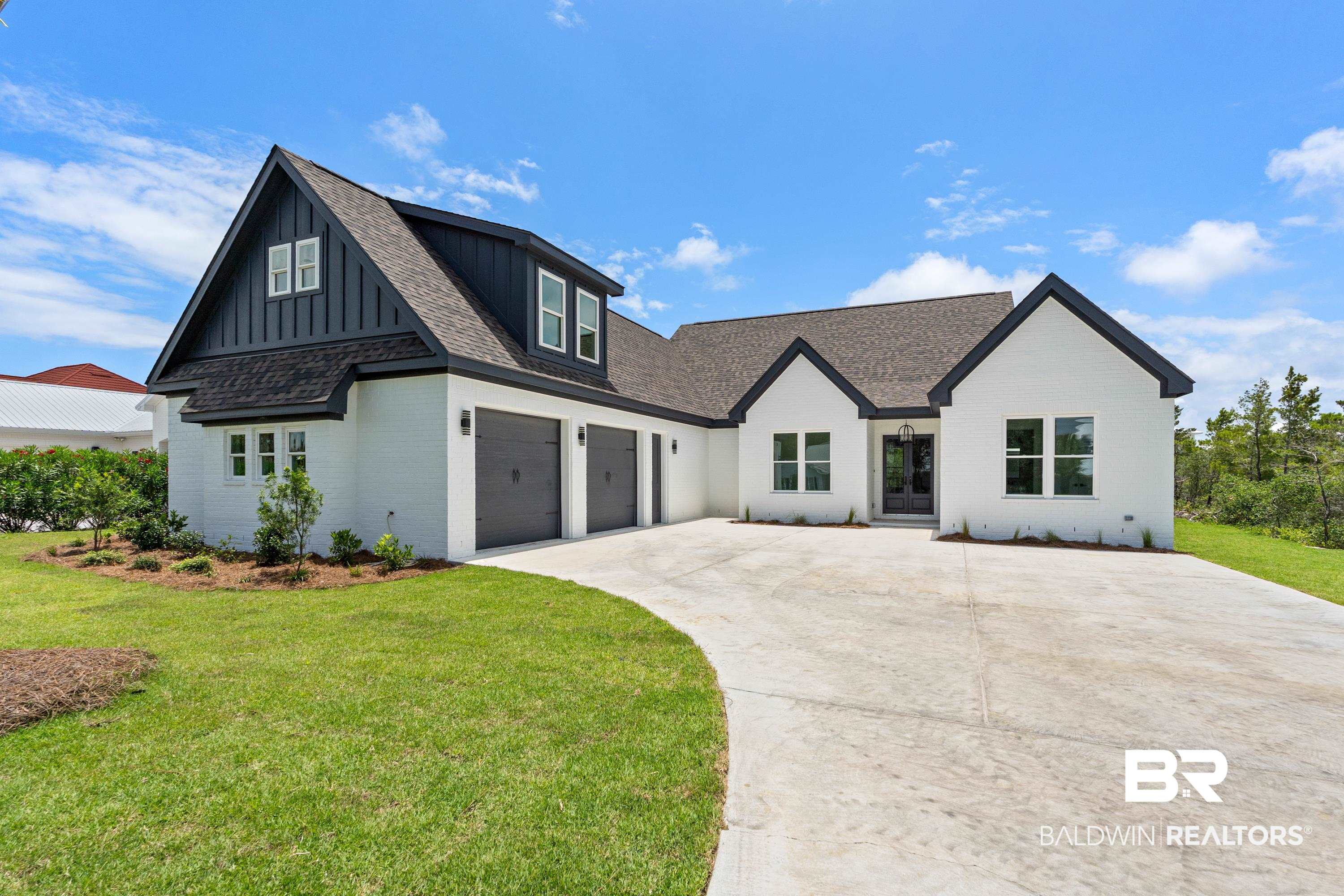 Modern inspired farmhouse featuring board and batten siding, concrete driveway, brick siding, a front yard, and a shingled roof