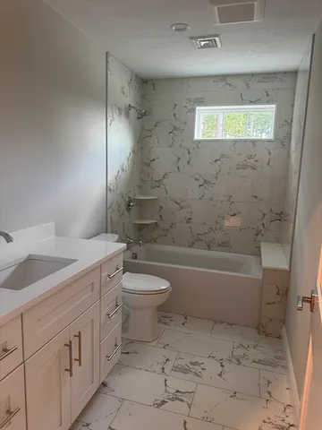 a bathroom with a granite countertop toilet a sink and bathtub