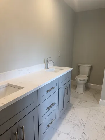 a spacious bathroom with a toilet sink and mirror