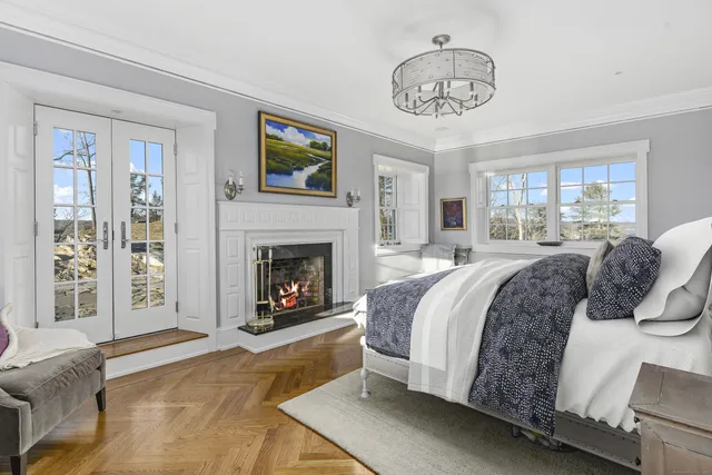 a spacious bedroom with a bed a fireplace and a chandelier