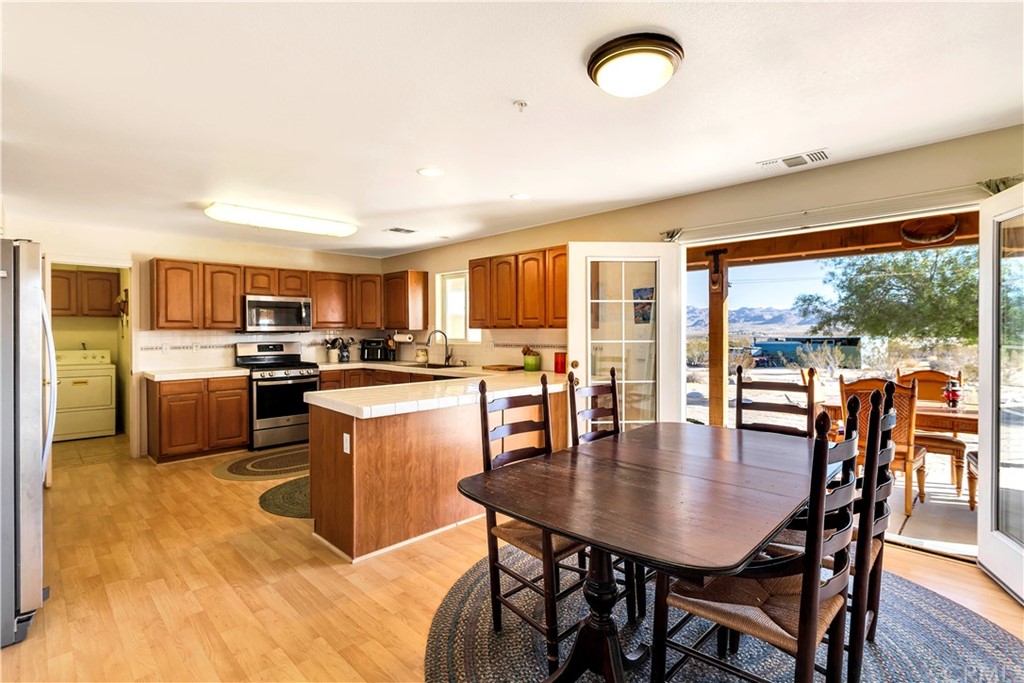 62401 Sunflower Road Joshua Tree, CA 92252 - Photo 13 of 75 a kitchen with a table chairs microwave and cabinets