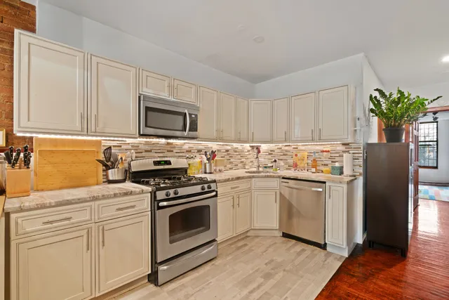 a kitchen with white cabinets stainless steel appliances and wooden floor