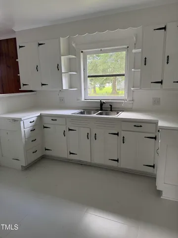 a kitchen with granite countertop a sink white cabinets and a window