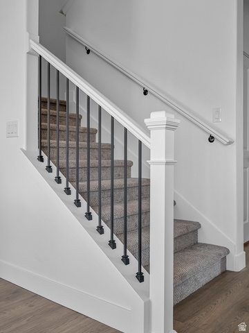 1380 West 2350 South, Unit 16 Perry, UT 84302 - Photo 13 of 34 Carpeted staircase with black iron balusters, white newel post, and wood-finish flooring