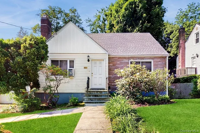 a front view of a house with a yard and potted plants