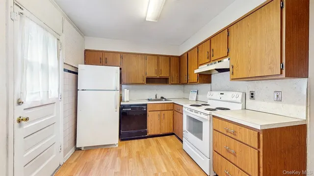 a kitchen with a refrigerator a stove a sink dishwasher and wooden cabinets with wooden floor