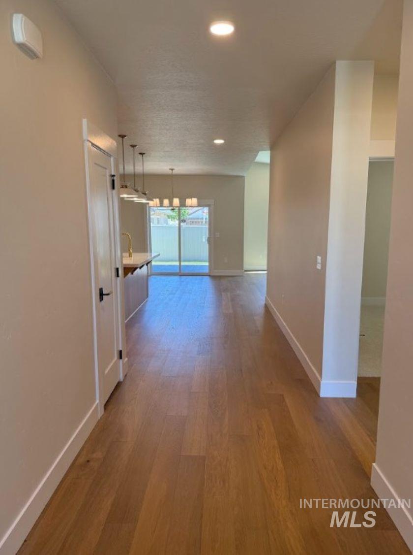 683 West Wrangler Street Meridian, ID 83646 - Photo 17 of 23 Hallway featuring wood-finish flooring, recessed lighting, and a modern interior door with matte black hardware