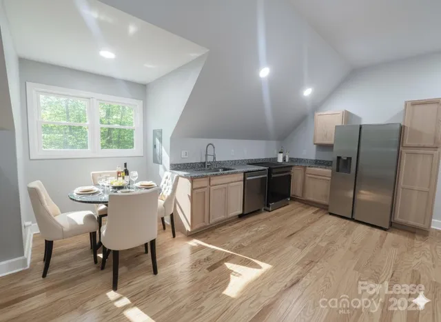 a kitchen with stainless steel appliances a table chairs sink refrigerator and cabinets