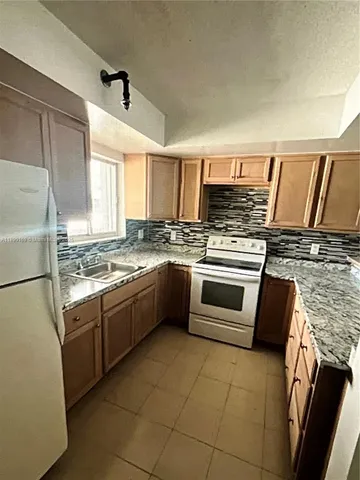a kitchen with granite countertop a stove top oven and cabinets