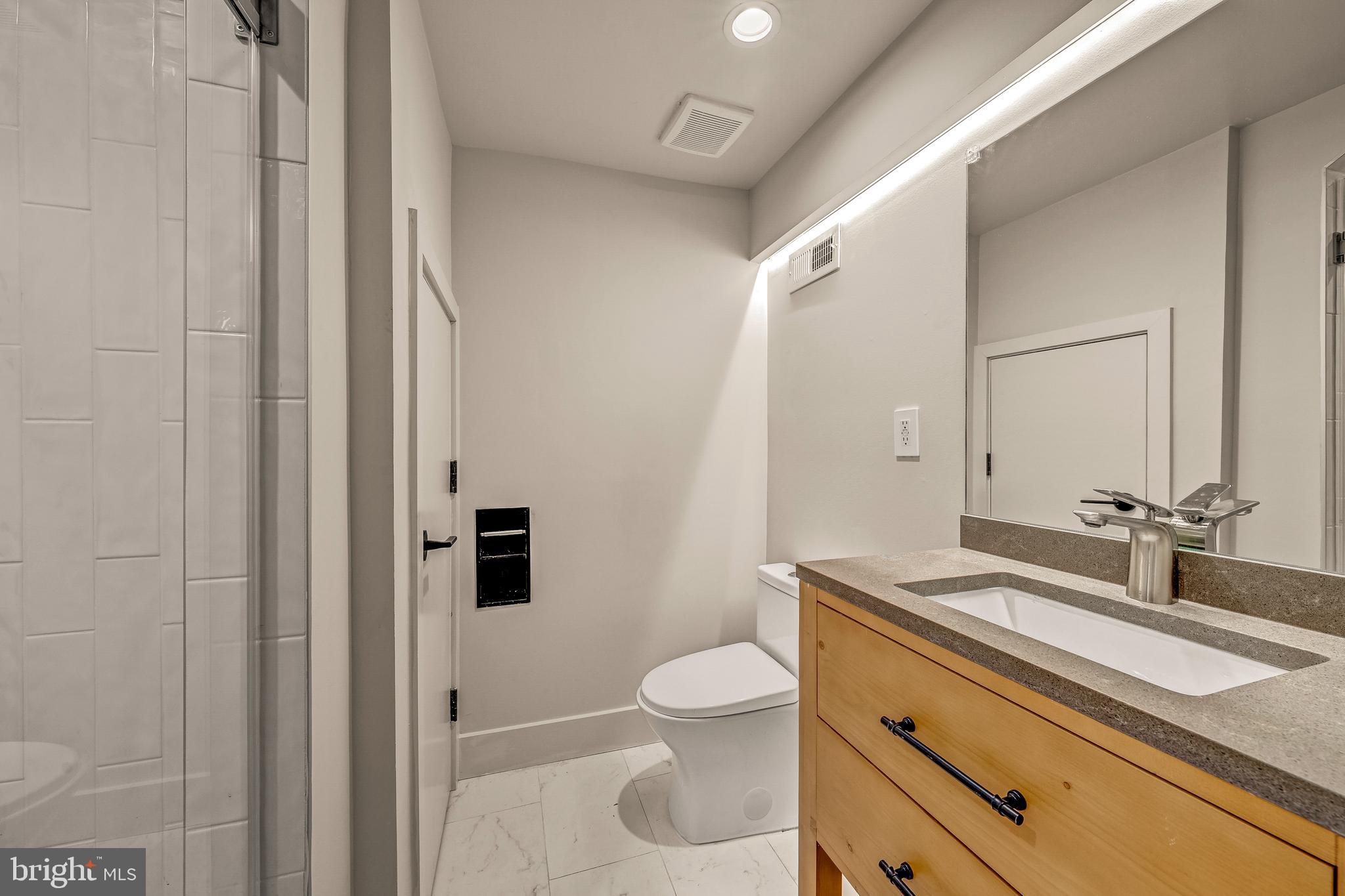 5921 Chesterbrook Road McLean, VA 22101 - Photo 69 of 76 a bathroom with a granite countertop sink a toilet and a mirror