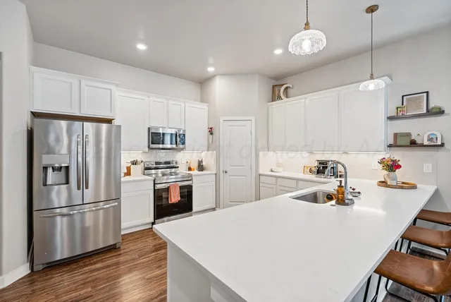 a kitchen with a refrigerator a stove and white cabinets