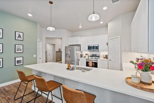 a kitchen with stainless steel appliances kitchen island granite countertop a dining table and chairs in it