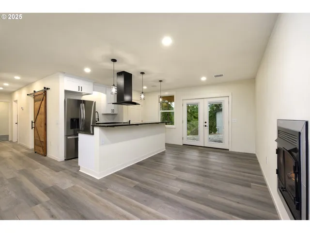 a view of kitchen with kitchen island wooden floors and stainless steel appliances