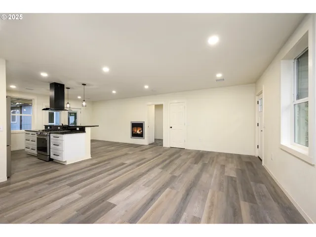 a kitchen with stainless steel appliances granite countertop a refrigerator a sink a stove and a wooden floors