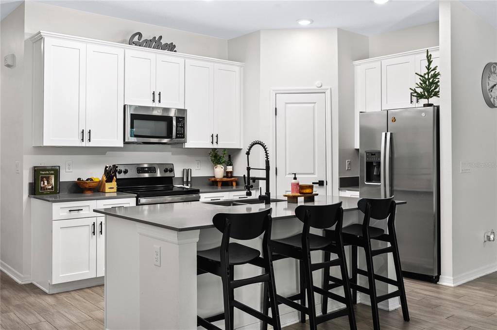2518 Hoptree Lane Edgewater, FL 32141 - Photo 7 of 28 a kitchen with stainless steel appliances a stove a sink refrigerator and white cabinets with wooden floor