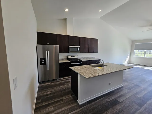 a kitchen with stainless steel appliances granite countertop a refrigerator and a stove top oven