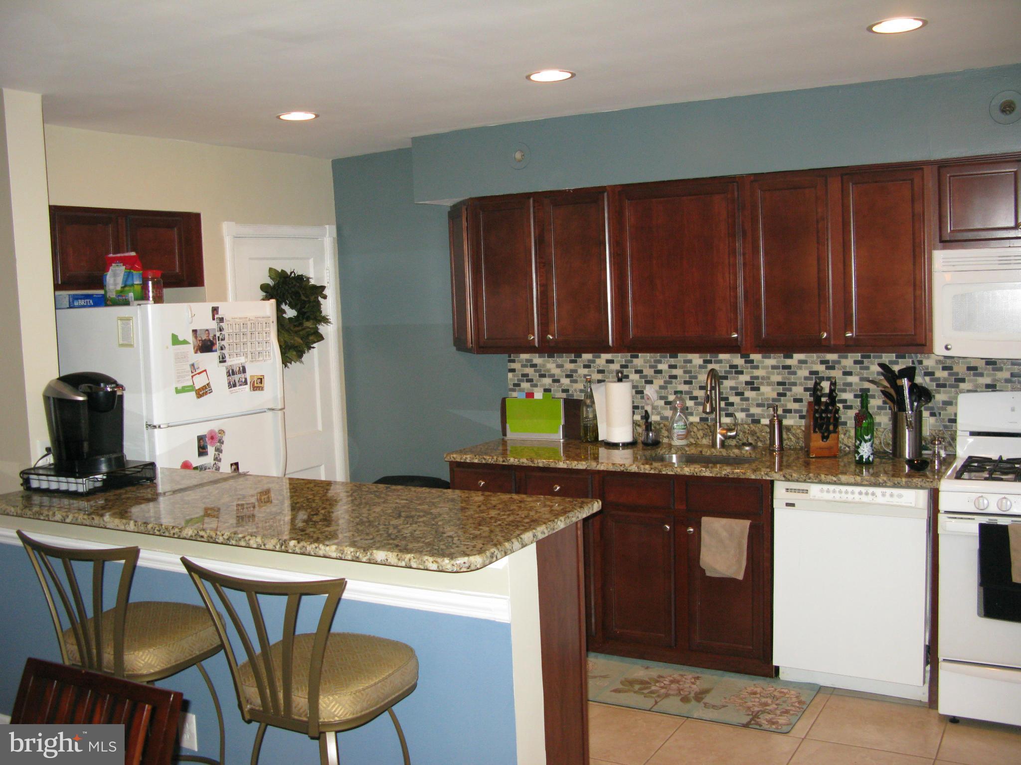 60 Murdock Road Baltimore, MD 21212 - Photo 9 of 30 a kitchen with granite countertop a table chairs stove top oven and cabinets