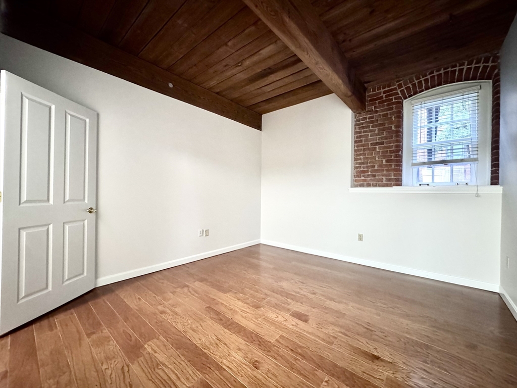 4 Bishop Street, Unit G11 Framingham, MA 01702 - Photo 12 of 24 an empty room with wooden floor and windows