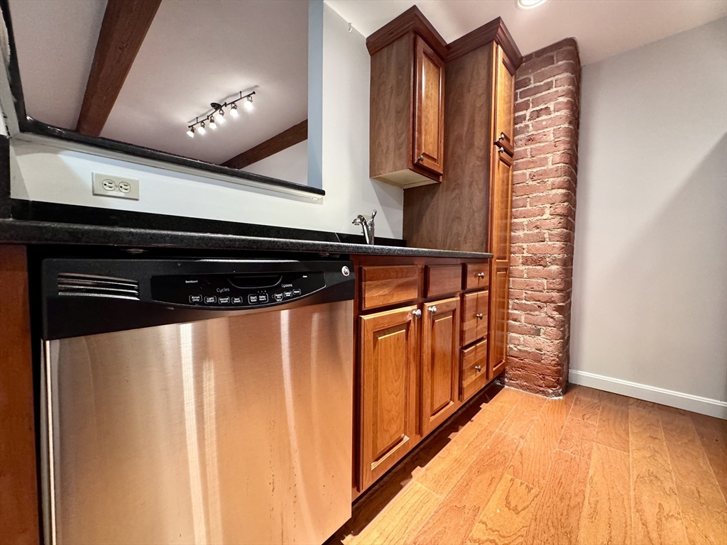 4 Bishop Street, Unit G11 Framingham, MA 01702 - Photo 3 of 24 a hallway with stainless steel appliances granite countertop a stove and a microwave