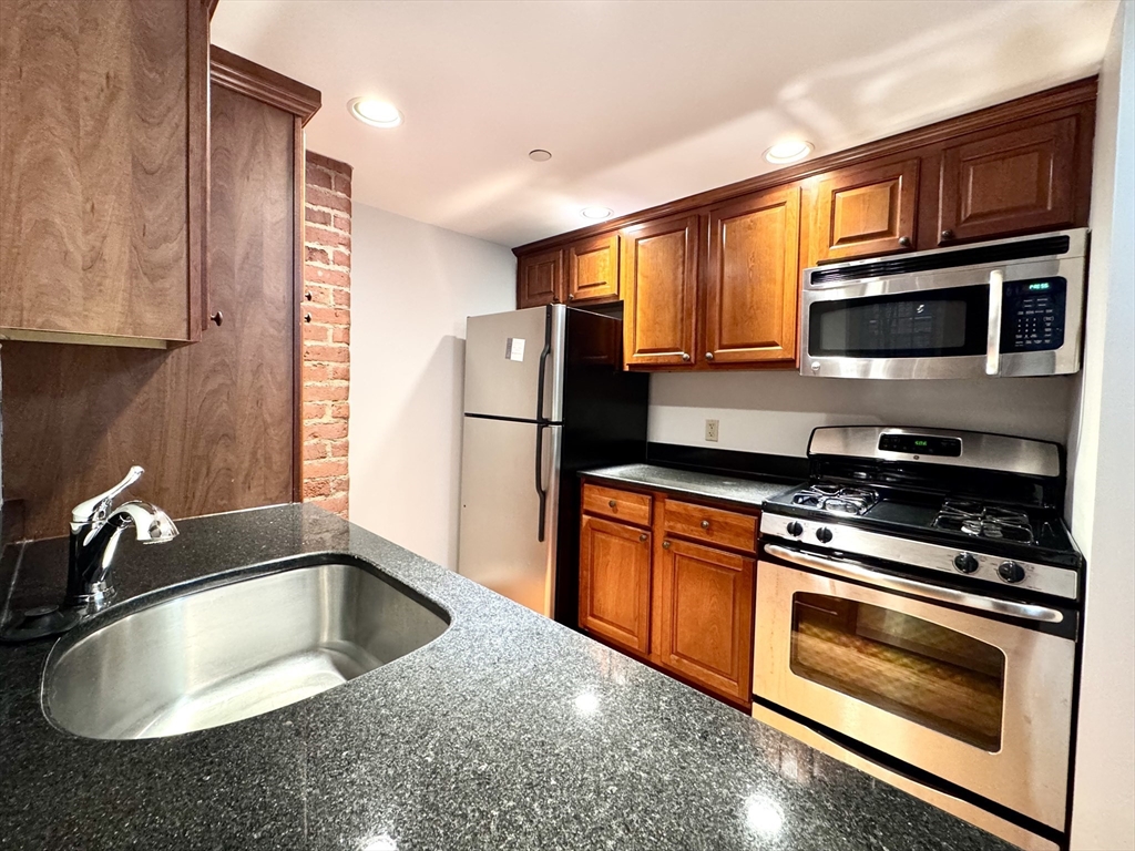 4 Bishop Street, Unit G11 Framingham, MA 01702 - Photo 4 of 24 a kitchen with granite countertop a sink and a refrigerator