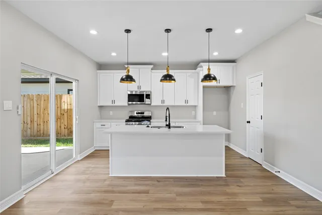 a large white kitchen with lots of white appliances cabinets and a wooden floor