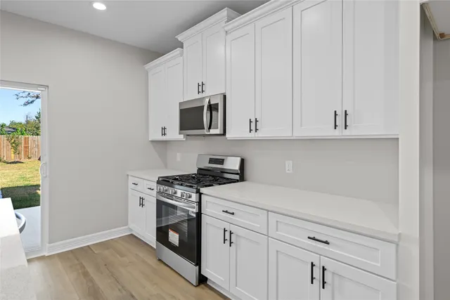 a large white kitchen with lots of counter space and stainless steel appliances