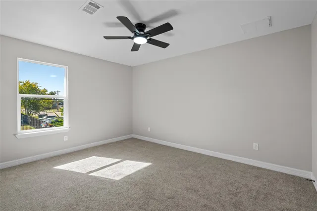 an empty room with windows and a ceiling fan