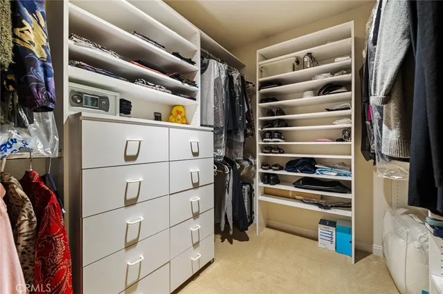 a view of walk in closet with clothes and shoes