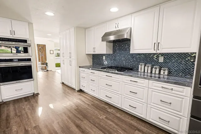 a kitchen with granite countertop white cabinets and stainless steel appliances