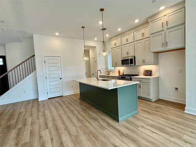 a kitchen with stainless steel appliances granite countertop a sink a stove and a refrigerator