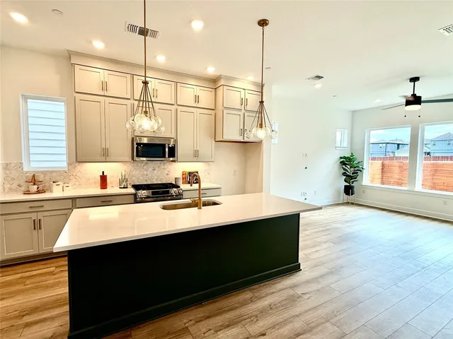 a kitchen with stainless steel appliances granite countertop a sink a stove and a wooden floor