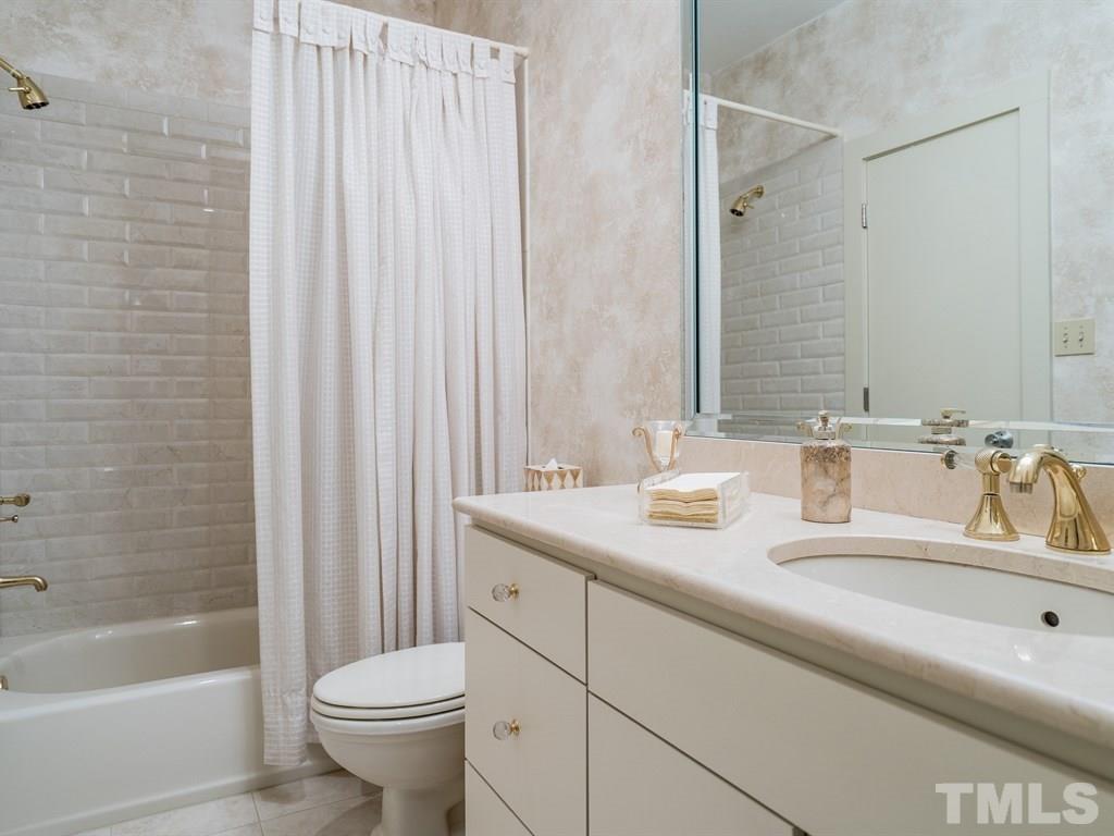 10000 Grafton Road Raleigh, NC 27615 - Photo 13 of 25 Updated 1st floor bathroom with subway tiles in shower, 12 inch tiles on flooring, marble counter, and light colored raised vanity.