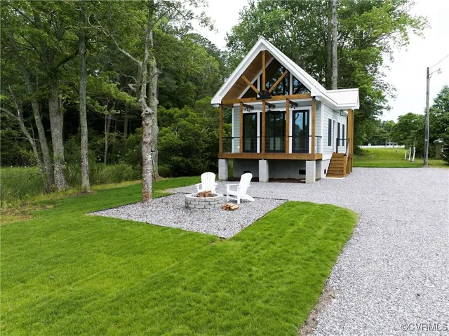 a view of house with a big yard and potted plants and large trees