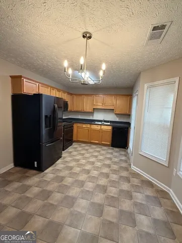 a large kitchen with stainless steel appliances kitchen island granite countertop a refrigerator and a sink