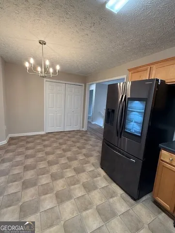 a view of a refrigerator in kitchen and an empty room