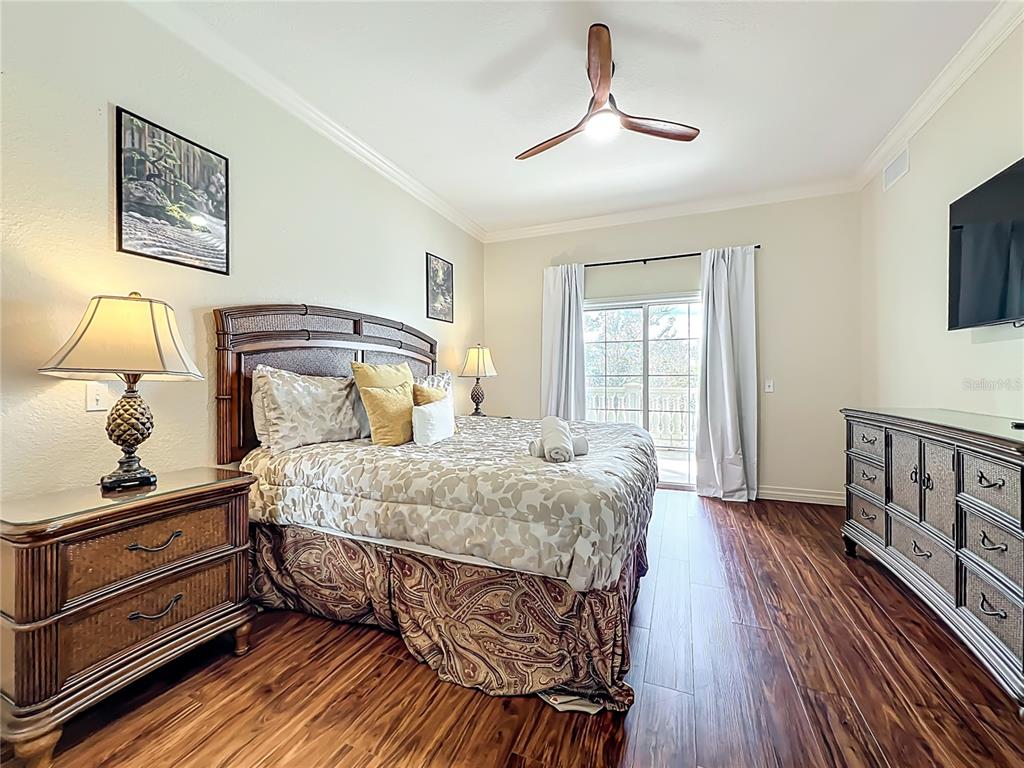 7660 Whisper Way, Unit 402 Reunion, FL 34747 - Photo 32 of 65 a bedroom with a bed and wooden floor
