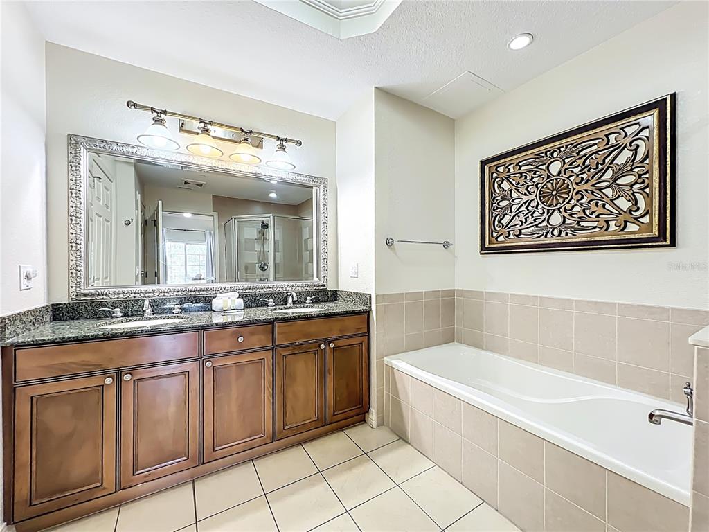 7660 Whisper Way, Unit 402 Reunion, FL 34747 - Photo 38 of 65 a bathroom with a granite countertop sink a large mirror a bathtub and shower