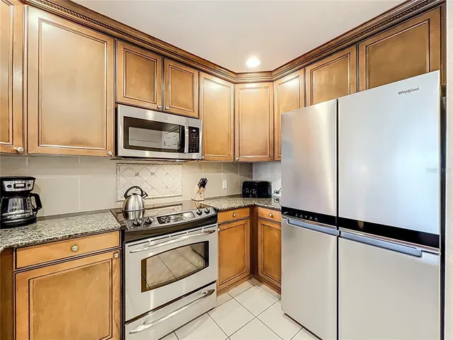 a kitchen with stainless steel appliances granite countertop a refrigerator a stove top oven a sink dishwasher and white cabinets with wooden floor