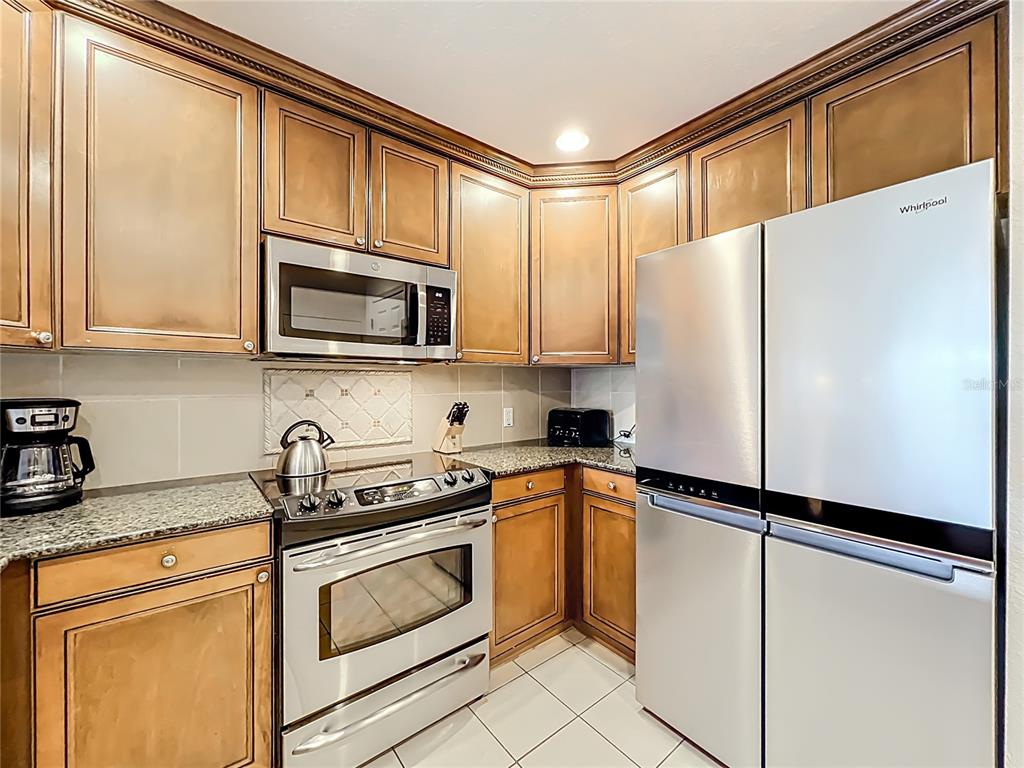 7660 Whisper Way, Unit 402 Reunion, FL 34747 - Photo 6 of 65 a kitchen with stainless steel appliances granite countertop a refrigerator sink and microwave