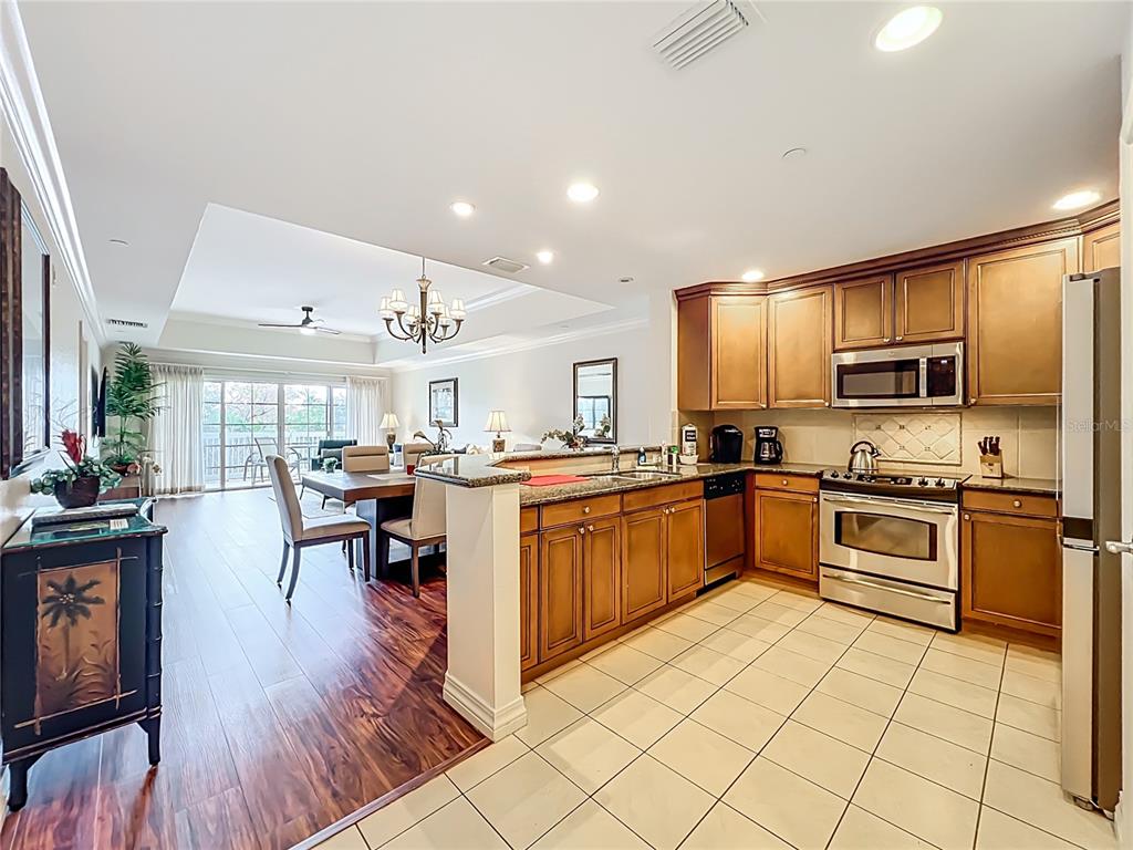 7660 Whisper Way, Unit 402 Reunion, FL 34747 - Photo 7 of 65 a kitchen with stainless steel appliances granite countertop a refrigerator a stove top oven a sink dishwasher and white cabinets with wooden floor