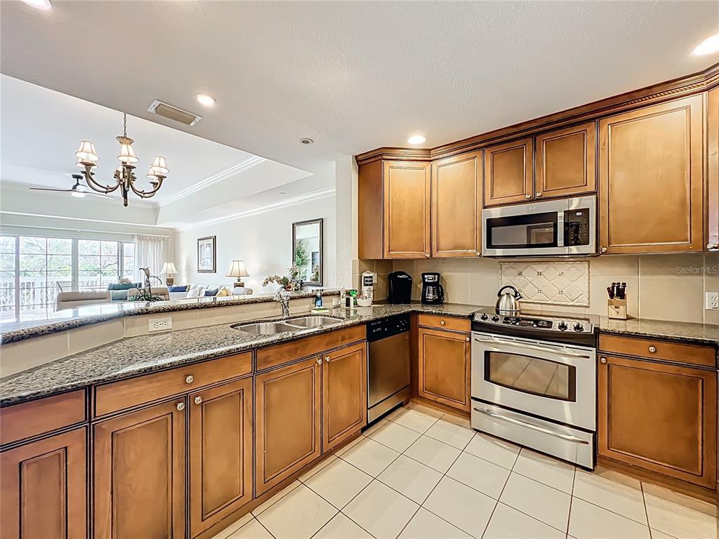7660 Whisper Way, Unit 402 Reunion, FL 34747 - Photo 8 of 65 a kitchen with stainless steel appliances granite countertop a stove top oven a sink dishwasher and a microwave oven on the blue kitchen countertops