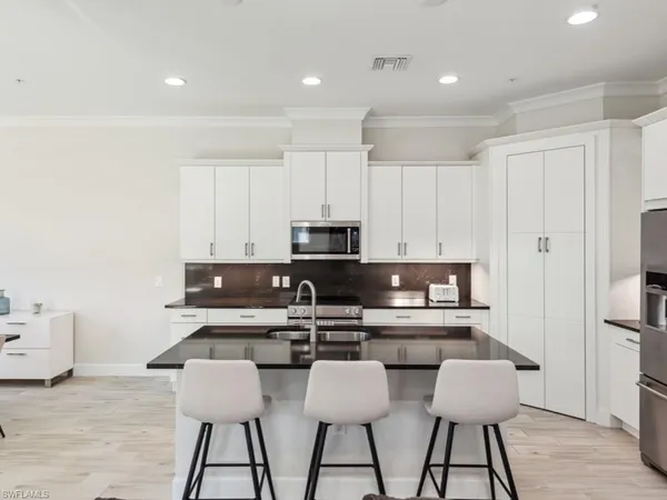 a kitchen with kitchen island white cabinets and stainless steel appliances