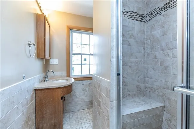 a bathroom with a granite countertop sink a mirror and shower