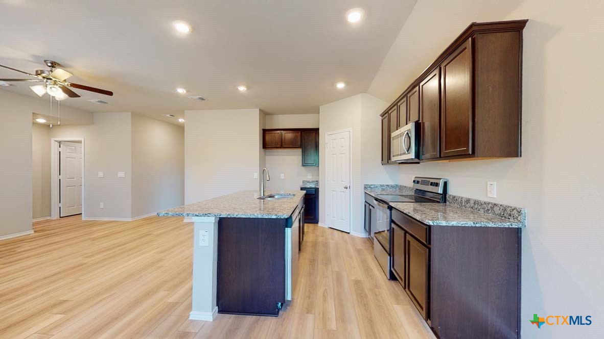 549 Hector Loop Georgetown, TX 78626 - Photo 6 of 22 a kitchen with stainless steel appliances granite countertop a sink dishwasher a stove and a refrigerator with wooden floor