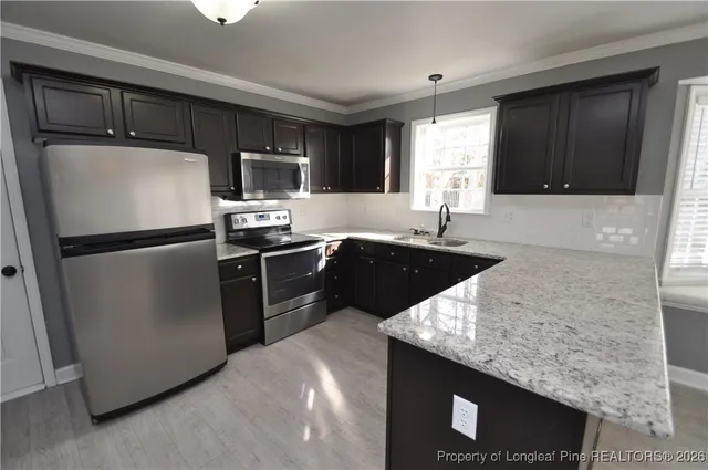 a kitchen with granite countertop a refrigerator stove and microwave