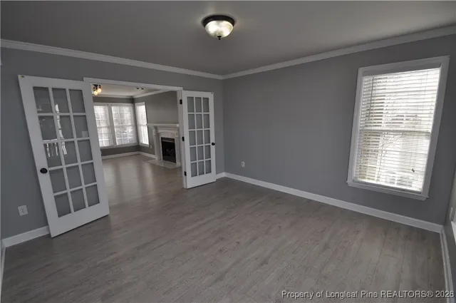 a view of an empty room with wooden floor fireplace and a window