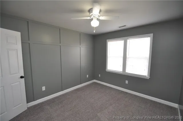 an empty room with a chandelier fan and closet area